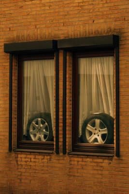 a brick building with two windows and a car tire in the window
