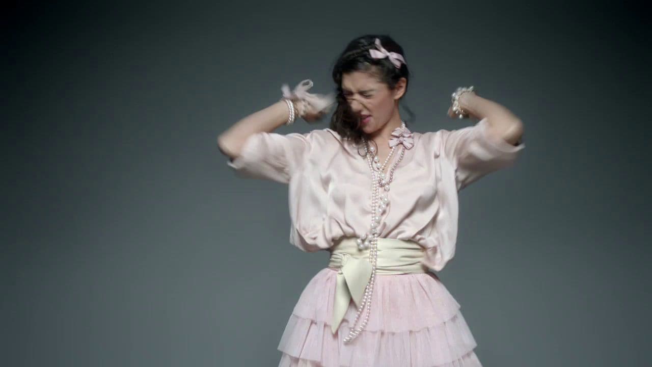 a woman in a pink dress with her hands on her head