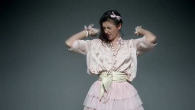 a woman in a pink dress with her hands on her head