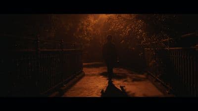 a person standing on a sidewalk in the dark