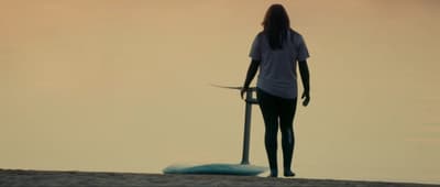 a woman standing on a beach holding a surfboard