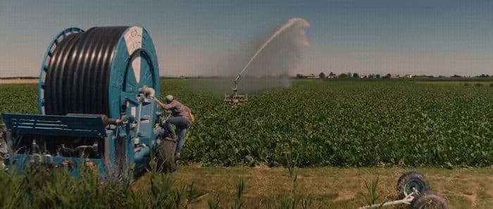 a tractor spraying water on a field of crops