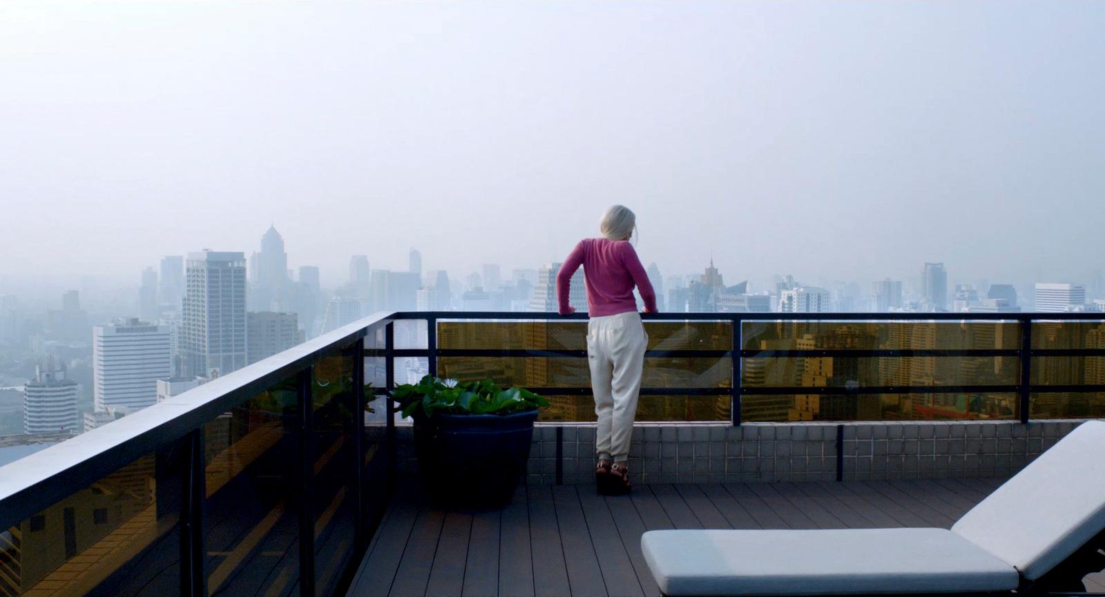 a woman standing on a balcony overlooking a city