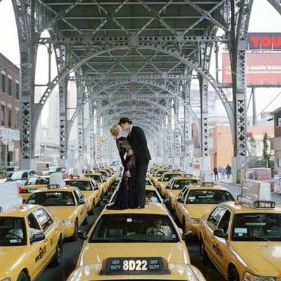 a man and a woman kissing in front of a line of taxi cabs