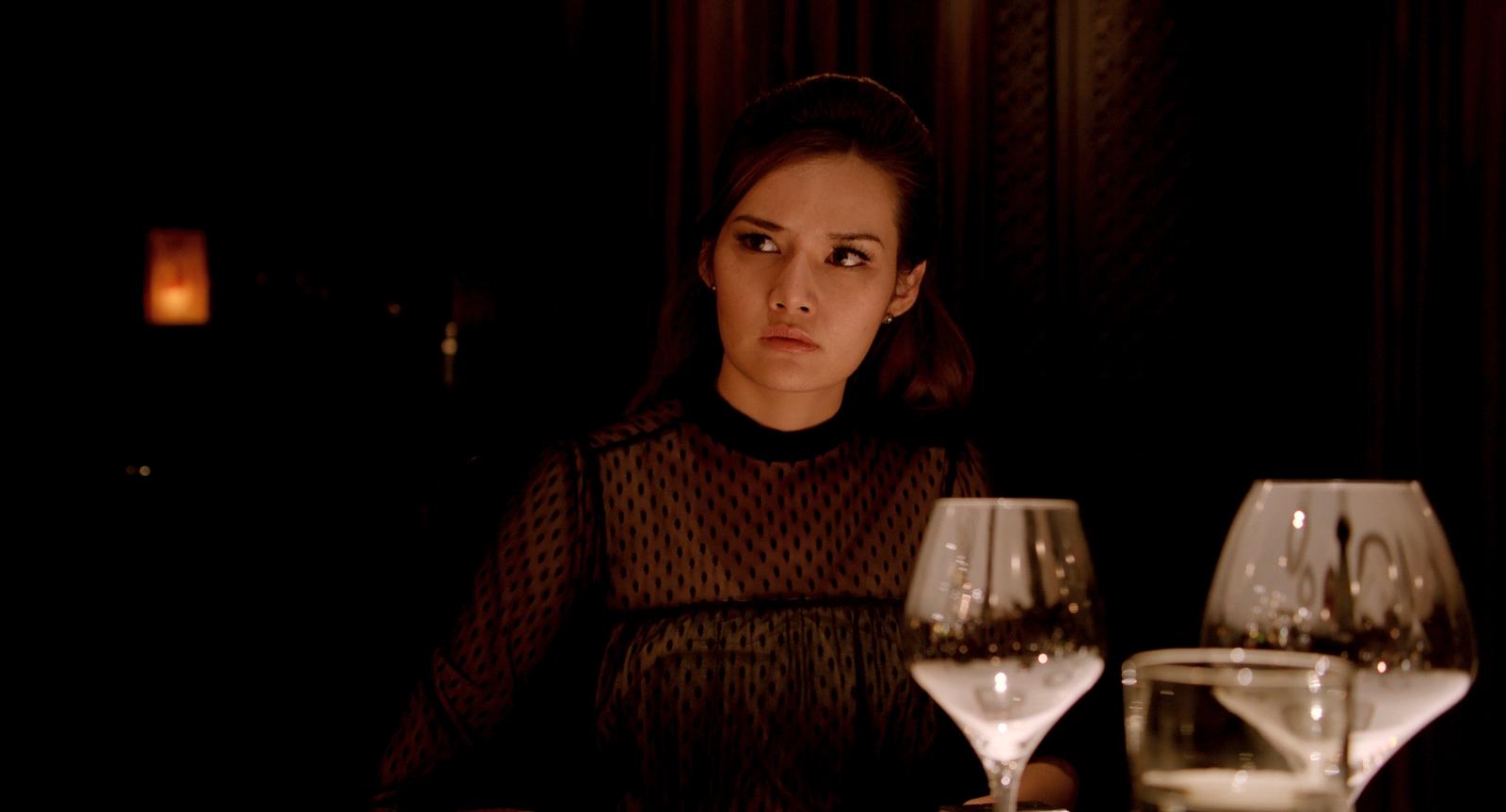 a woman sitting at a table with two wine glasses