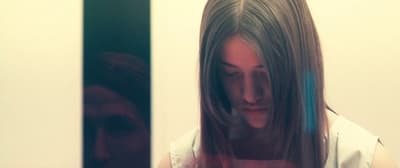 a woman looking at her cell phone in a mirror