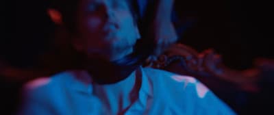 a man in a white shirt and tie in a dark room