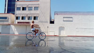 a man riding a bike down a street next to tall buildings