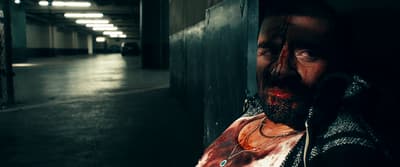 a man with blood on his face standing next to a wall