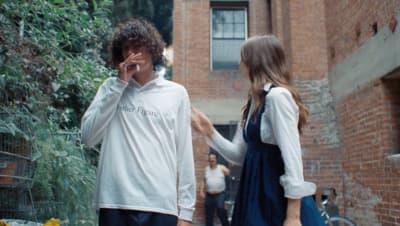 a man and a woman talking to each other in an alley