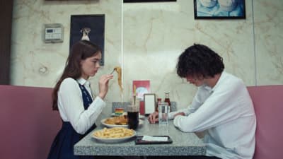 a man and woman sitting at a table eating pasta