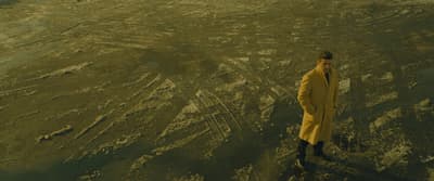a man in a yellow suit standing in the desert