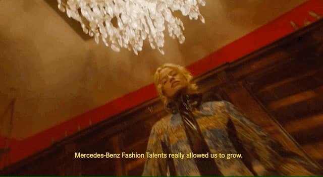 a woman standing under a chandelier in a room