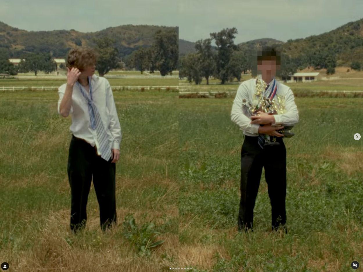 two men standing in a field with one talking on a cell phone