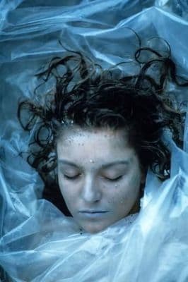 a woman with wet hair laying in a plastic bag