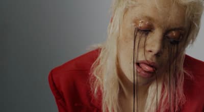 a woman with white hair and makeup has her eyes closed