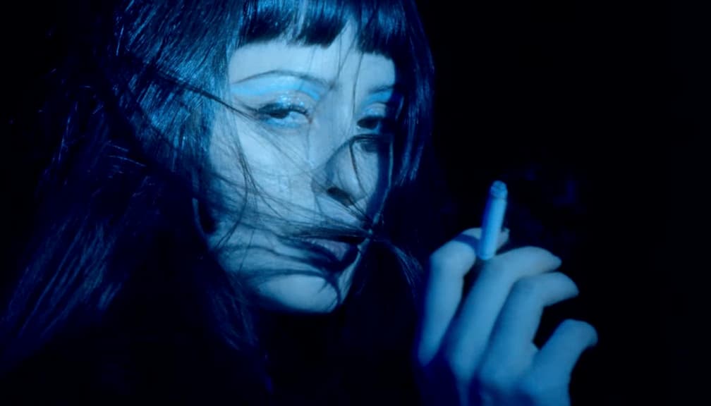 a woman is smoking a cigarette in the dark