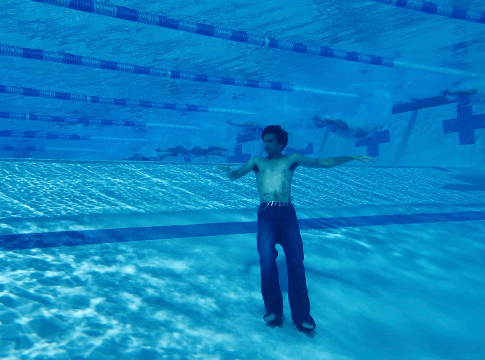 a man standing in a pool with his arms outstretched