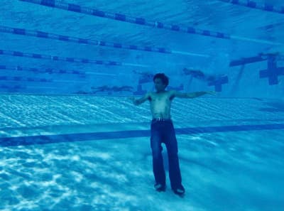 a man standing in a pool with his arms outstretched