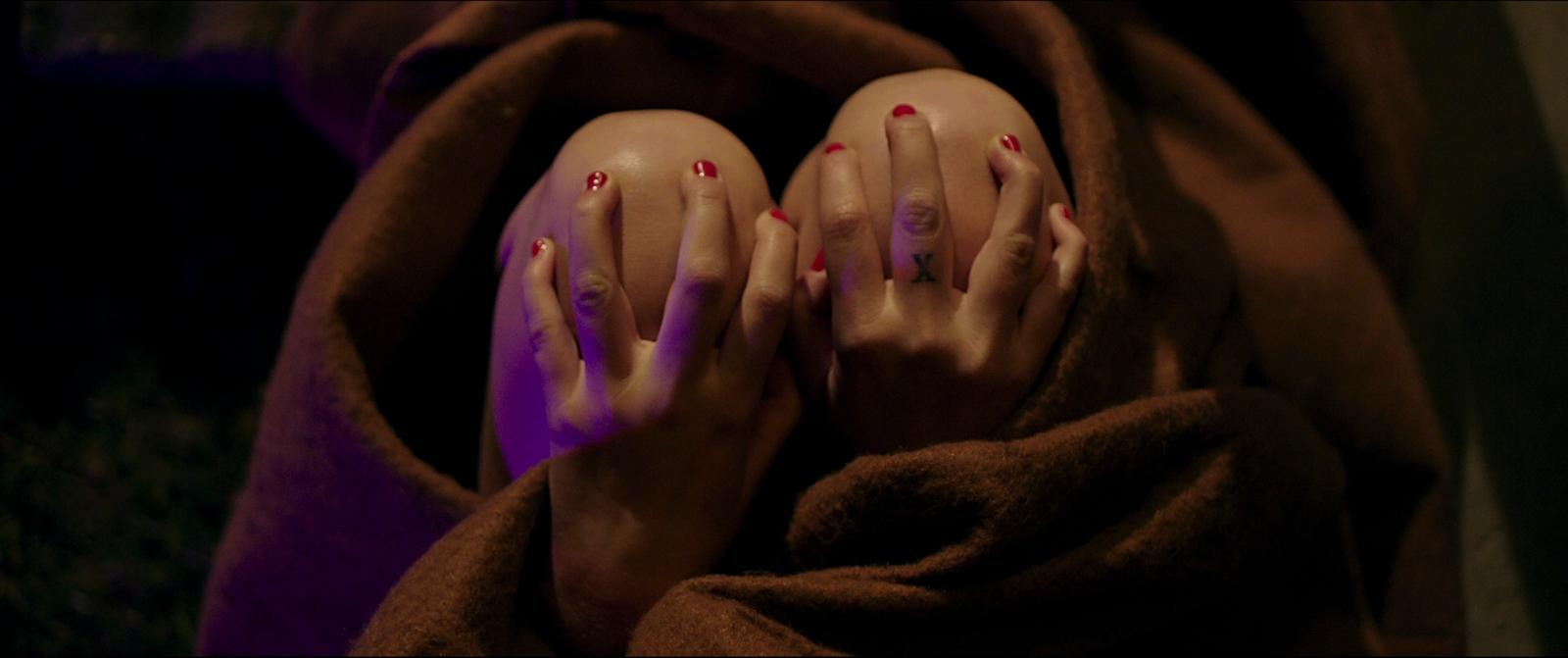 a person with long nails and red nails laying on a blanket