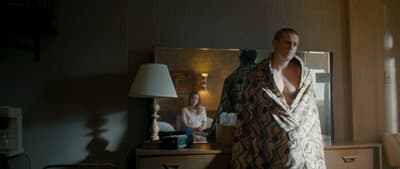 a man in a robe standing in front of a mirror
