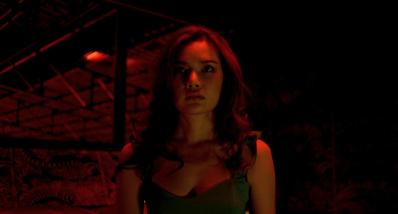 a woman in a green dress standing in a dark room