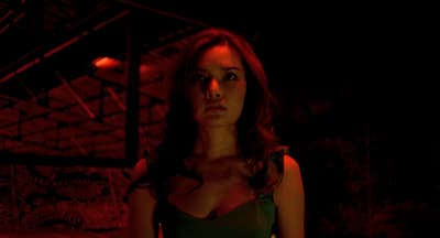 a woman in a green dress standing in a dark room