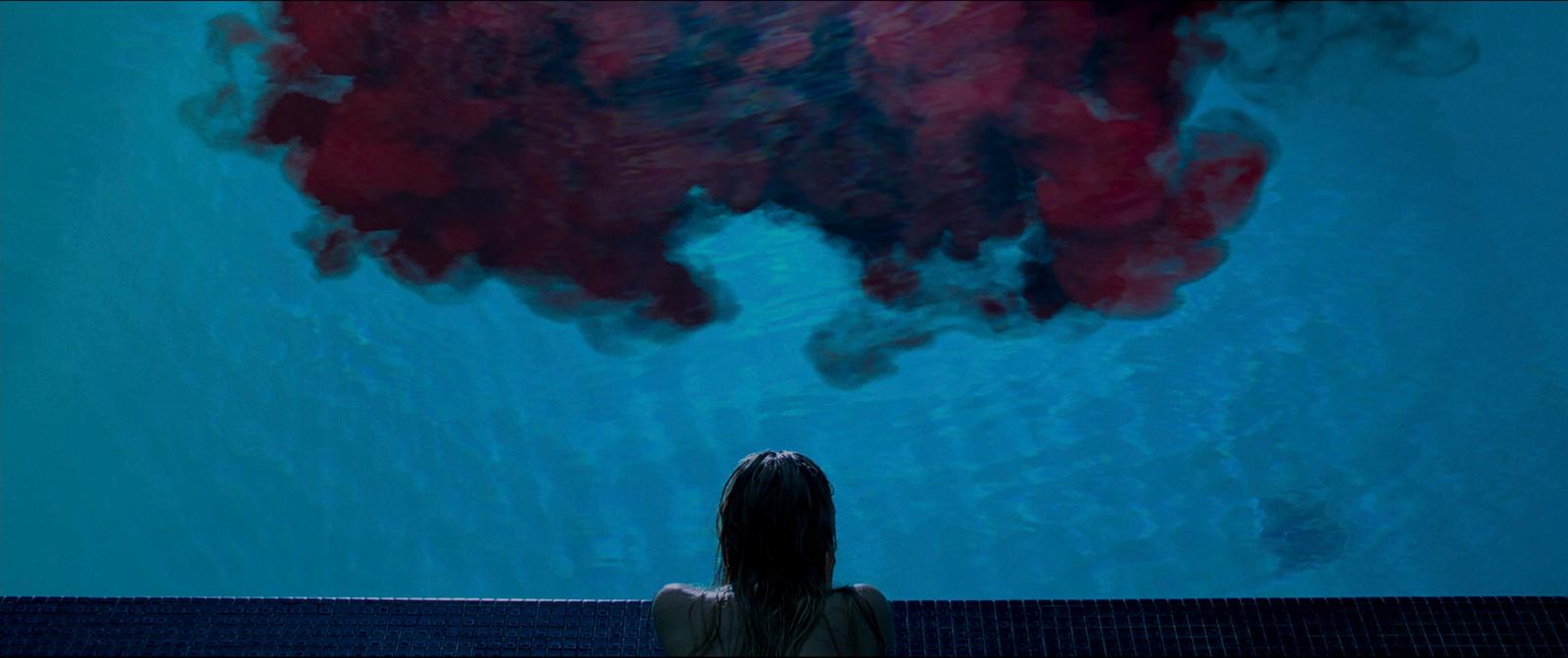 a woman sitting in front of a large painting