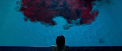 a woman sitting in front of a large painting