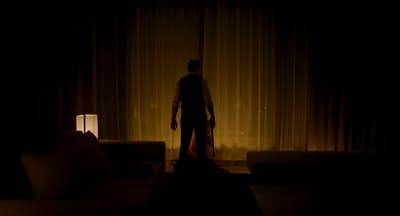 a man standing in a dark room next to a couch