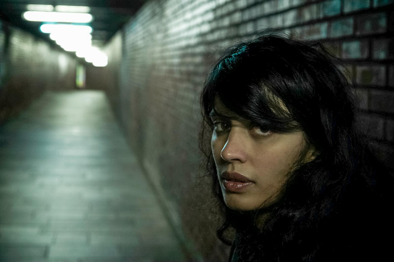 a woman is standing in an alleyway