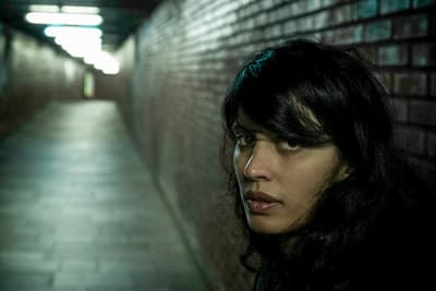 a woman is standing in an alleyway