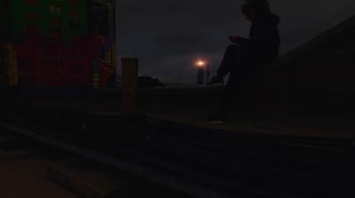 a person sitting on a ledge at night using a cell phone