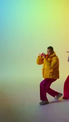 a man in a yellow jacket standing next to a woman in a red dress
