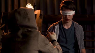 a man with a blindfold on his face standing next to a stuffed animal
