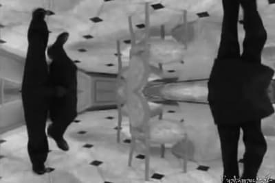 a black and white photo of two people walking in front of a mirror