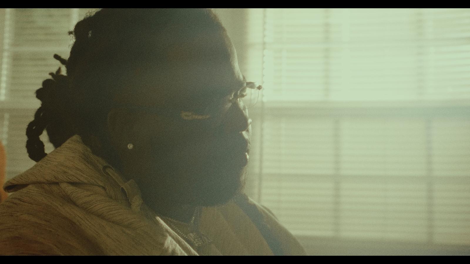 a man with dreadlocks standing in front of a window
