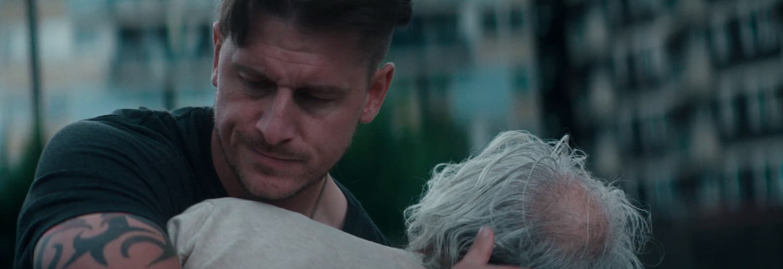 a man with a tattooed arm hugging another man