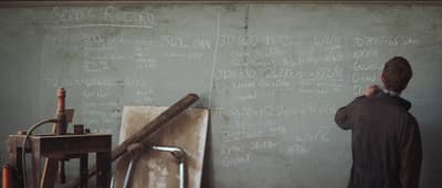 a man writing on a wall with chalk