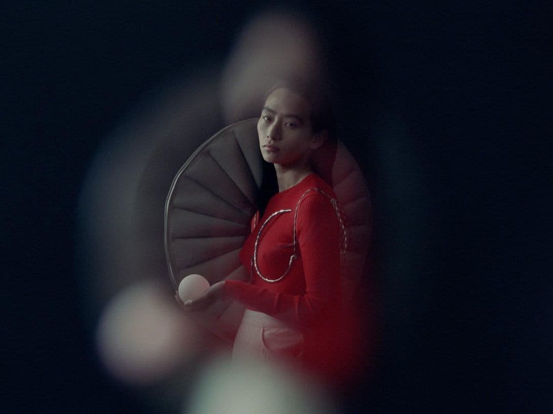 a woman in a red dress standing in front of a spiral staircase