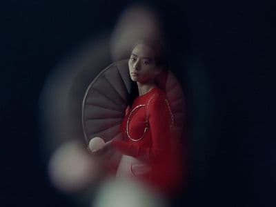 a woman in a red dress standing in front of a spiral staircase