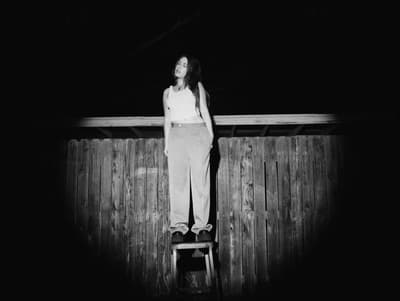 a black and white photo of a woman standing on a ladder