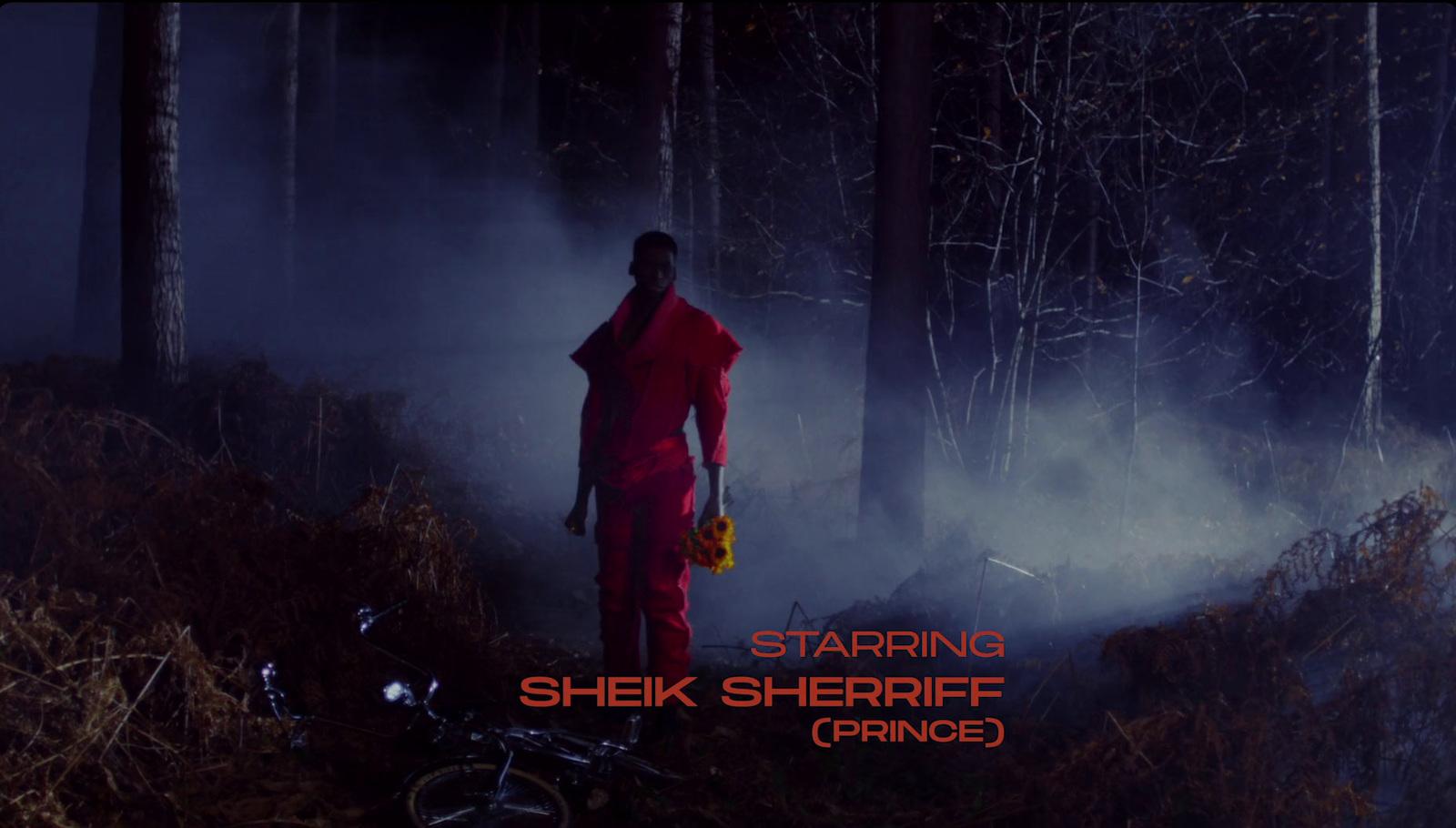 a man in a red outfit standing in the woods