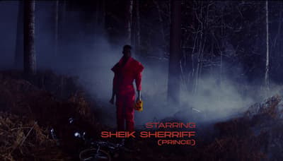 a man in a red outfit standing in the woods