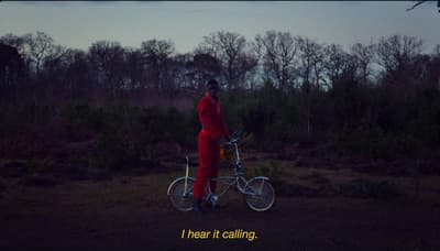 a man in a red jumpsuit standing next to a bicycle