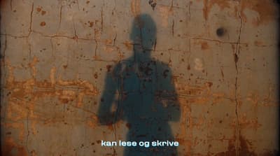 a shadow of a person standing in front of a rusted wall