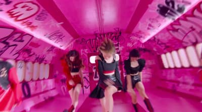 a group of women in a pink room with graffiti on the walls