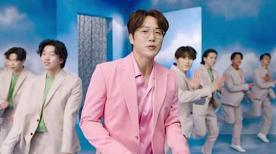 a man in a pink suit standing in front of a group of other men