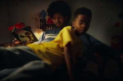 a man sitting next to a child on a bed