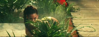 a woman sitting on the ground next to a plant